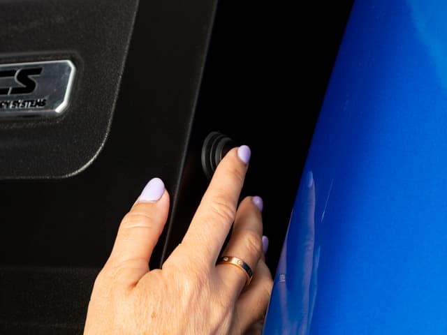 A hand pressing the push button on the side of the headboard