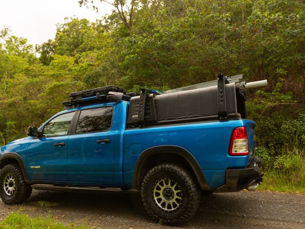 A blue RAM 1500 with the RCS canopy closed on a dirt road
