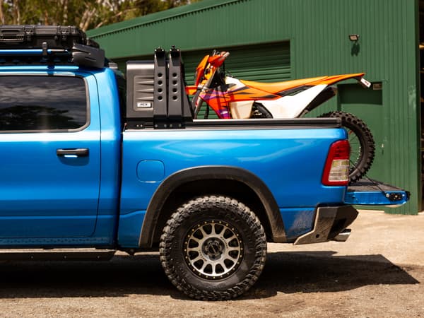 A RAM 1500 side on, dirt bike loaded under the open canopy