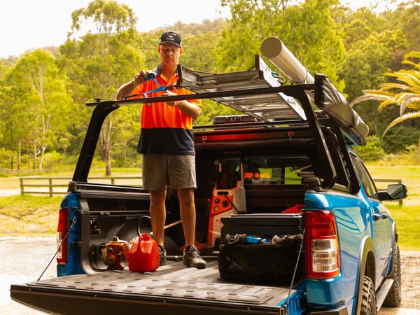 A tradie standing in the open tub of a RAM 1500 with the canopy retracted