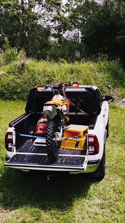 A dirt bike loaded in the open tub of a white HiLux with the RCS canopy retracted